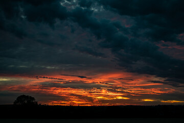 Beautiful wide angle view for dramatic sunset sky with clouds, astonishing sun set in bright colors on British agricultural grounds, most amazing view in UK, high contrast and saturation photography