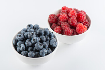 Fresh berries raspberries and blueberries in bowls isolated on white background, top view