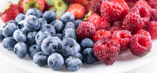 Fresh delicious berries Strawberries, blueberries and raspberries close-up in a white plate