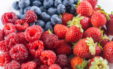 Fresh tasty berries background. Strawberries, blueberries and raspberries close up top view