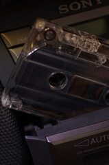 Audio cassette - in a dark light, against the background of a tape recorder.