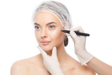 Young woman, beauty clinic patient, ready for facelifting procedures, doctor in gloves uses skin marker, isolated on white background