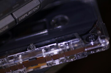 Audio cassette - in a dark light, against the background of a tape recorder.