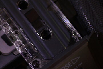 Audio cassette - in a dark light, against the background of a tape recorder.