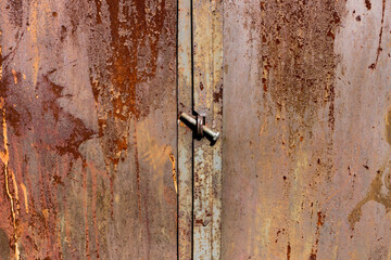 Grunge background. Metalrusty door closed with a bolt