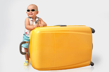 Todler with a big yellow suitcase.