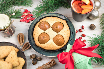 Home-made pie with pears decorated with a red bow, a Cup with a Christmas drink and cookies on a white background. The concept of the new year 2021 and Christmas.