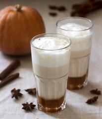 Homemade pumpkin latte in tall glasses and pumpkin on a linen tablecloth. Rustic style.