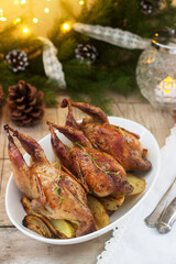 Baked quail with potatoes and onions on a festive background. Rustic style.
