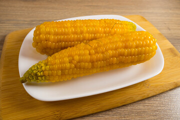 Corn lies on canvas. Fresh corn closeup. Corn cob on a plate. Sweet corn on background for food ingredients and cooking concept.