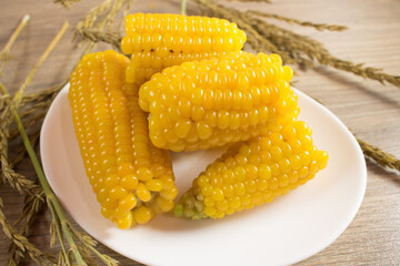 Corn lies on canvas. Fresh corn closeup. Corn cob on a plate. Sweet corn on background for food ingredients and cooking concept.