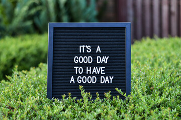 "Its a good day to have a good day" words written on a black letterbox at the outdoor terace. Blurred background.