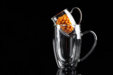 sandthorn berries in a transparent mug on a black background
