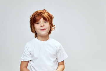 Portrait of red-haired boy cropped view white t-shirt smile studio 