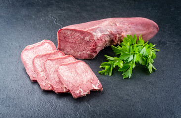 Traditionelle gekochte Rinderzunge mit Petersilie angeboten als close-up auf einem rustikalen...