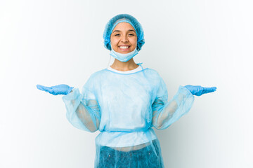 Young surgeon latin woman isolated on white background makes scale with arms, feels happy and confident.