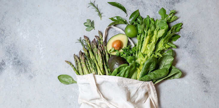 Healthy food ingredients green vegetables and fruits in eco linen bag, zero waste and clean eating concept. gray background