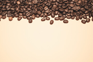 Frame made of scattered coffee beans on pink background with empty space.
