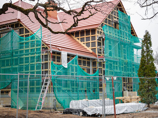 The process of restoration of the old house. The object is covered with a protective net. Near building material and supporting structures. Housing recovery concept. Close-up.