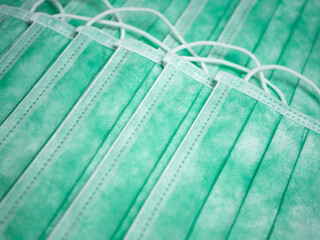 Close-up of many stacked medical or surgical green color protective masks with ear loops as background. The concept of medical supplies or accessories for personal protection.