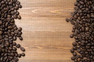 Vertical frame of spilled coffee beans on wood background with empty space.