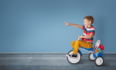 Little boy is carrying many gifts on bicycle.