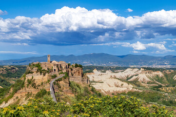 Fototapeta na wymiar Civita di Bagnoregio, picturesque panoramic view of the medieval town surrounded by clouds. The village on the top a plateau of volcanic tuff known as The Dying Town, Viterbo provence, Lazio, Italy.