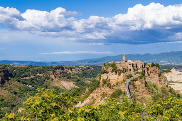 Fototapeta na wymiar Picturesque panoramic view of Civita di Bagnoregio, the medieval town surrounded by clouds. The village on the top a plateau of volcanic tuff known as The Dying Town, Viterbo provence, Lazio, Italy.