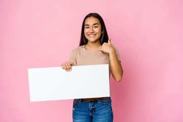 Fototapeta na wymiar Young asian woman holding a blank paper for white something over isolated background showing a mobile phone call gesture with fingers.