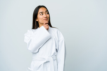 Young asian woman doing karate isolated on white background looking sideways with doubtful and skeptical expression.