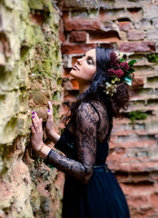 A woman in a dark dress on the background of old red brick ruins