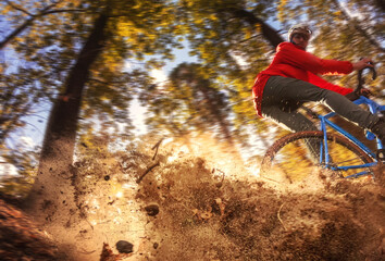 Cyclist in the forest rides along the trail, raising up dust from the rear wheel after a skid. Low angle view. Extreme sports concept.