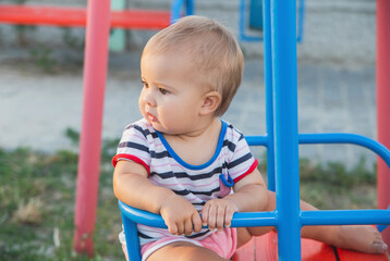 Fototapeta na wymiar Blonde baby sitting on a swing at sunset