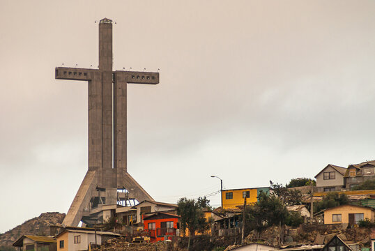 Coquimbo, Chile - December 7, 2008: Closeup of tall Millennium Cross Trinity surrounded by houses in different colors under blownish cloudscape.