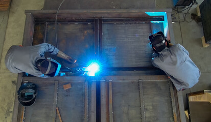 Welder welding a metal part in a dark industrial environment