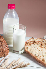 A glass of milk, sliced rustic bread and jam, on a white wooden board. Healthy food and farming concept