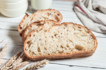 A glass of milk, sliced rustic bread and jam, on a white wooden board. Healthy food and farming concept