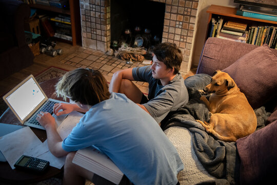 Two College Student Brothers Doing Math Homework With Their Dog Nearby