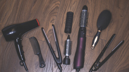 Hairdressing tools on a wooden background. Combs and hair dryer, hair straightener. Long hair...