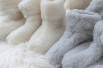 Soft white and beige fluffy background with woolen rugs and sheep fur socks. Winter chill out concept. Cozy Nordic Christmas in Hygge style. Comfortable woolen clothes for autumn and winter chill.