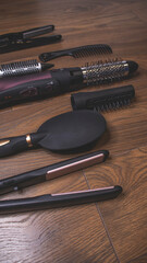 Hairdressing tools on a wooden background. Combs and hair dryer, hair straightener. Long hair curls. Extension hair care.