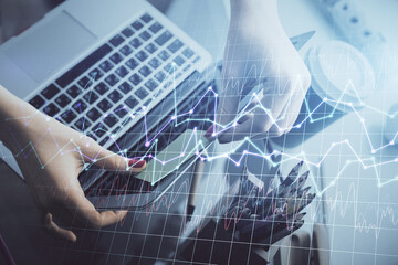 Double exposure of businesswoman hands typing on computer and financial graph hologram drawing. Stock market analysis concept.