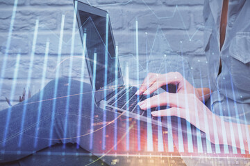 Multi exposure of woman hands typing on computer and forex chart hologram drawing. Stock market analysis concept.