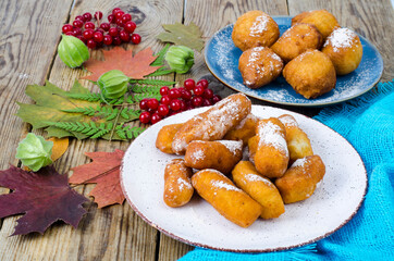 Sweet curd donuts buns with powdered sugar on wooden table