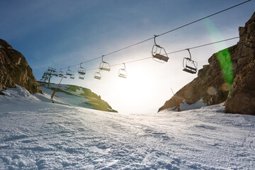Landscape of a ski lift in a ski resort in the Pyrenees with the sun behind over snowy slope