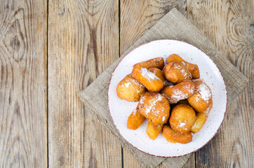 Sweet curd donuts buns with powdered sugar on wooden table