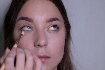 the process of applying makeup to a beautiful brunette. beauty, modeling and cosmetics concept. 