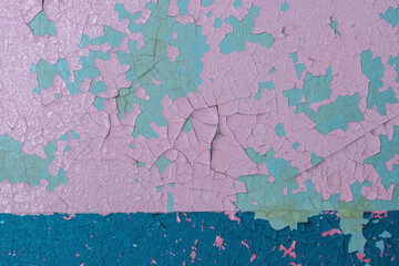 Pink peeling paint on the wall. Old concrete wall with cracked flaking paint. Weathered rough painted surface with patterns of cracks and peeling. High resolution texture for background and design.