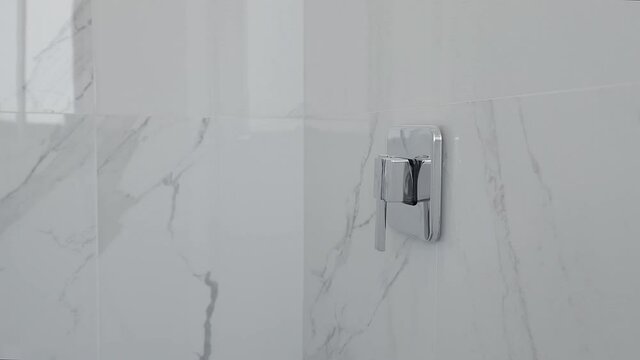 Llave de regadera con muros de m&aacute;rmol color blanco de un departamento de lujo. Contenido para proyectos inmobiliarios
