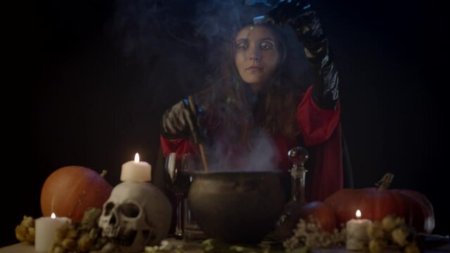 Young witch adding something sparkly in cauldron